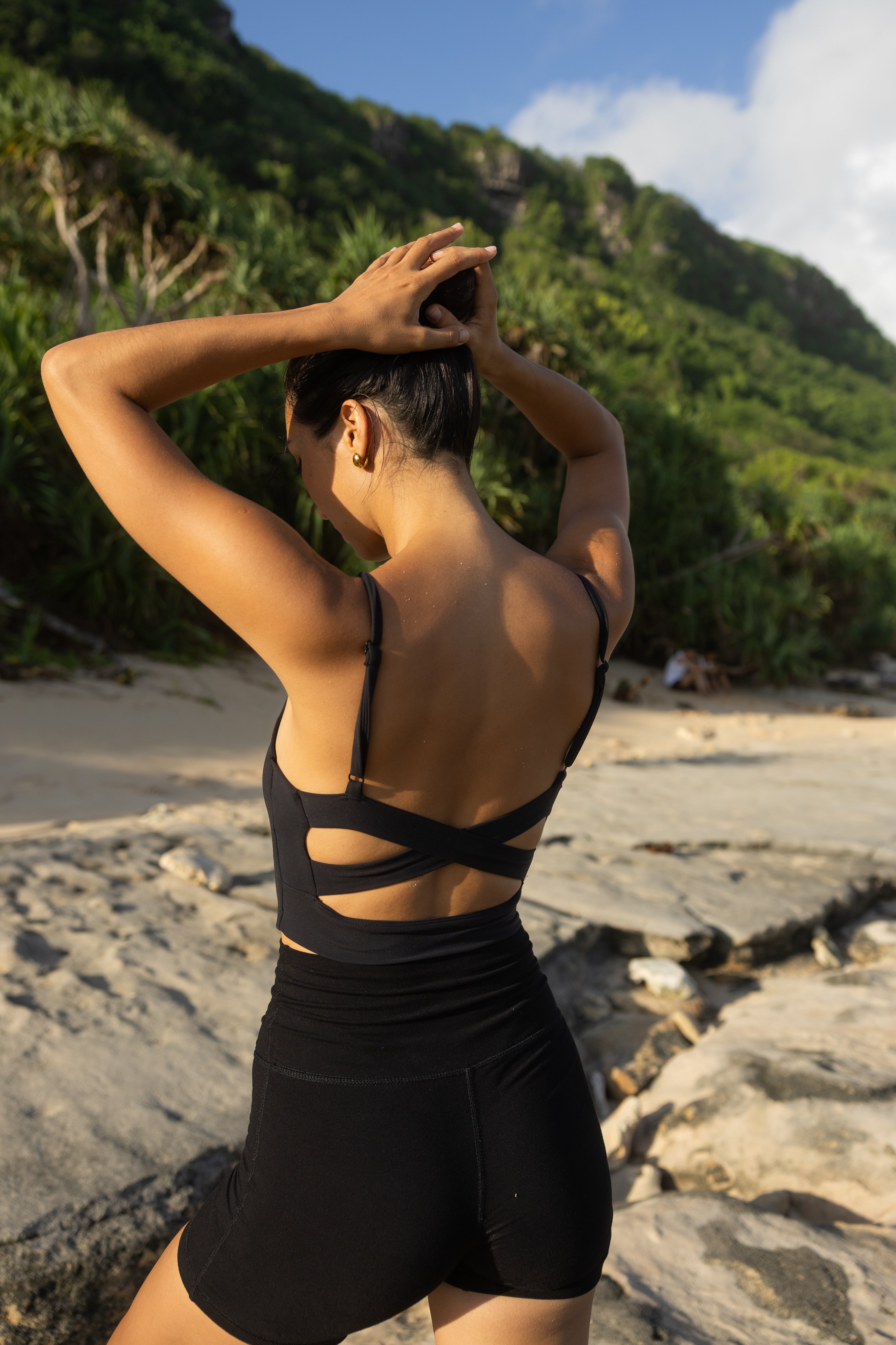 women in a black sustainable sports bra with a crisscross back detail.